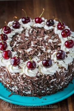 a chocolate cake with cherries and whipped cream toppings on a blue platter