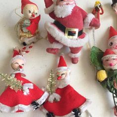 christmas ornaments including santa claus, elves and other toys are arranged on a white surface