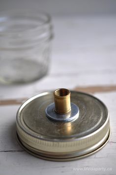 an empty glass jar sitting on top of a wooden table next to a metal lid