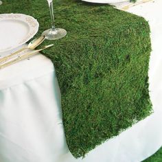 the table is covered with green moss and silverware, along with two wine glasses