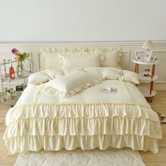 a white bed with ruffles and pillows on top of it in a room