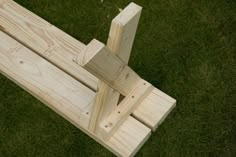 a wooden bench sitting in the grass on top of it's own legs and feet