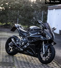 a black motorcycle parked on top of a cobblestone road