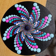 a wooden table topped with a black plate covered in lots of colorful dots and circles