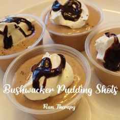 four desserts in plastic cups with chocolate and whipped cream on top, sitting on a table