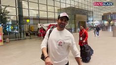 a man is walking through an airport with his suitcases and smiling for the camera