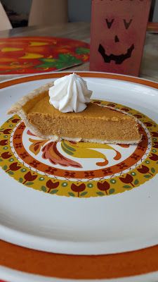 a slice of pumpkin pie sitting on top of a white plate with orange and yellow designs