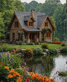 a house is surrounded by flowers and greenery next to a pond in front of it