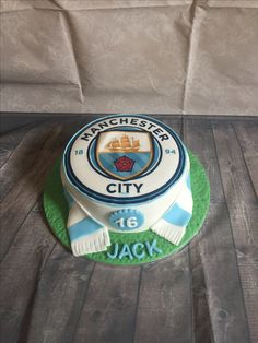 a cake that is sitting on top of a wooden table and has the name manchester city on it