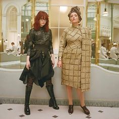 two women standing next to each other in front of a mirror with mirrors on the wall