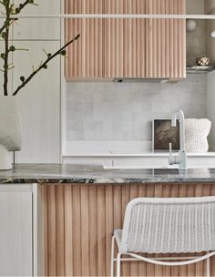 a white chair sitting in front of a counter top next to a potted plant