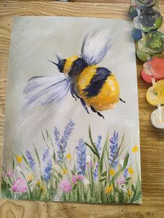 a painting of a bee on a piece of paper next to some paintbrushes