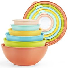 colorful bowls stacked in front of each other on a white background with an orange bowl next to them