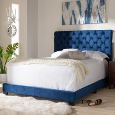 a blue upholstered bed in a white bedroom