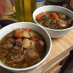 two white bowls filled with soup on top of a wooden table