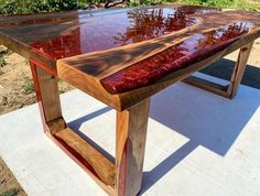 a wooden table sitting on top of a cement slab covered in red paint and wood