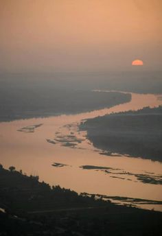 the sun is setting over a river with small islands in the water and trees on both sides