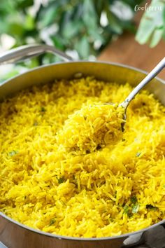 a pot filled with yellow rice on top of a wooden table