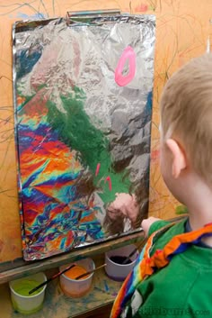 a young boy is painting on an easel