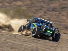 a blue monster truck driving through the desert