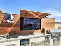 an outdoor grill with a television mounted to it's side