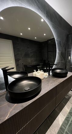 a bathroom with two sinks and a large mirror in the wall above it, along with black counter tops