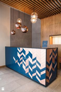 a blue and white reception counter with three lights hanging from it's ceiling above