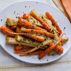 a white plate topped with carrots covered in seasoning on top of a table