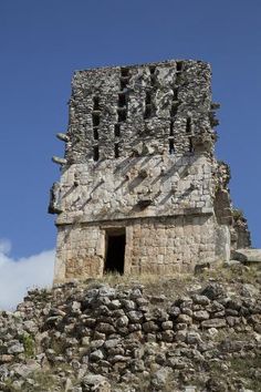 an old stone structure with a door on top of it in the middle of nowhere