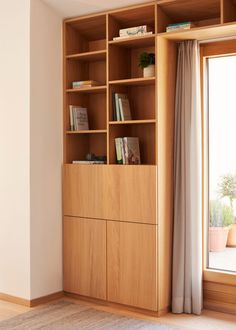 a wooden book shelf with books on it next to a window