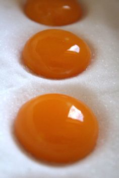 three orange eggs sitting on top of an egg tray in the middle of two rows