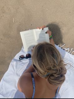 a woman reading a book on the beach