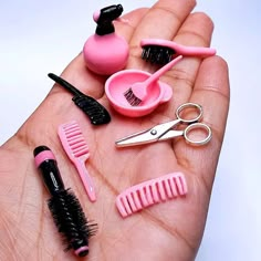 a person's hand holding several different types of hair brushes, combs and scissors