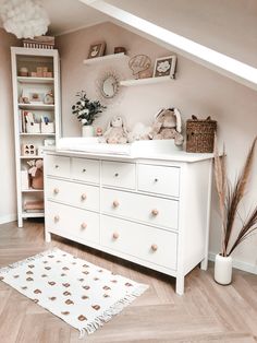 a baby's room with white furniture and accessories on the floor, including a dresser