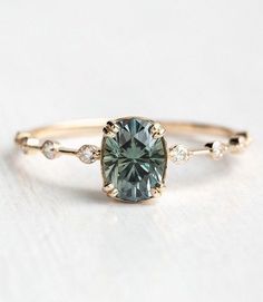 a ring with a green stone and white diamonds on the side, sitting on a table