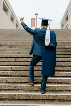 a man in a graduation cap and gown walking up some steps with his hand raised