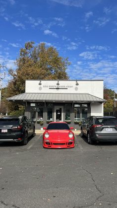 three porsches are parked in front of a building on a parking lot next to other cars