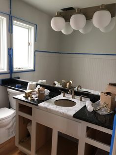 a bathroom with two sinks and a toilet in the middle, under construction on the wall