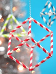 three ornaments hanging from a christmas tree in front of a blue sky and white lights