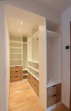 an empty walk in closet with white walls and wooden flooring is seen from the doorway