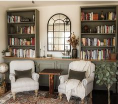 two chairs and a table in a room with bookshelves