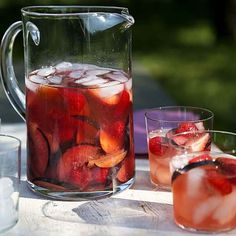 pitcher and glasses filled with liquid sitting on a table