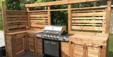 an outdoor kitchen made out of pallets and wooden planks with grill, sink and cabinets