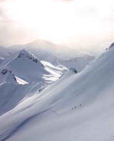 two skiers are skiing down a snowy mountain slope with mountains in the background and cloudy skies