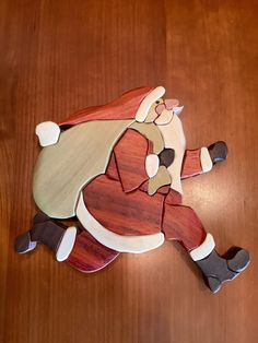 a wooden cutout of santa claus running on a wood floor with one foot in the air