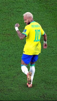 a soccer player in yellow and blue uniform kicking a ball on the field with his foot