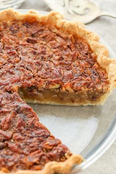 a pecan pie on a glass plate with one slice missing from it's crust