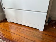 a white dishwasher sitting on top of a wooden floor next to a wall