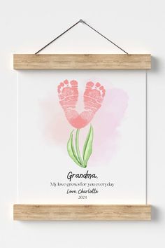 a wooden frame hanging on a wall with a pink flower in the middle and an inscription grandma