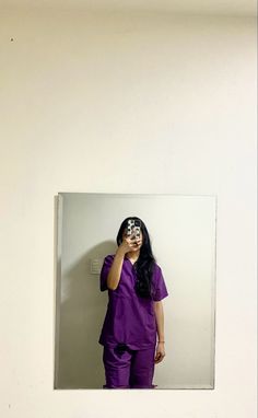 a woman in purple scrubs is taking a selfie with her cell phone while standing in front of a mirror